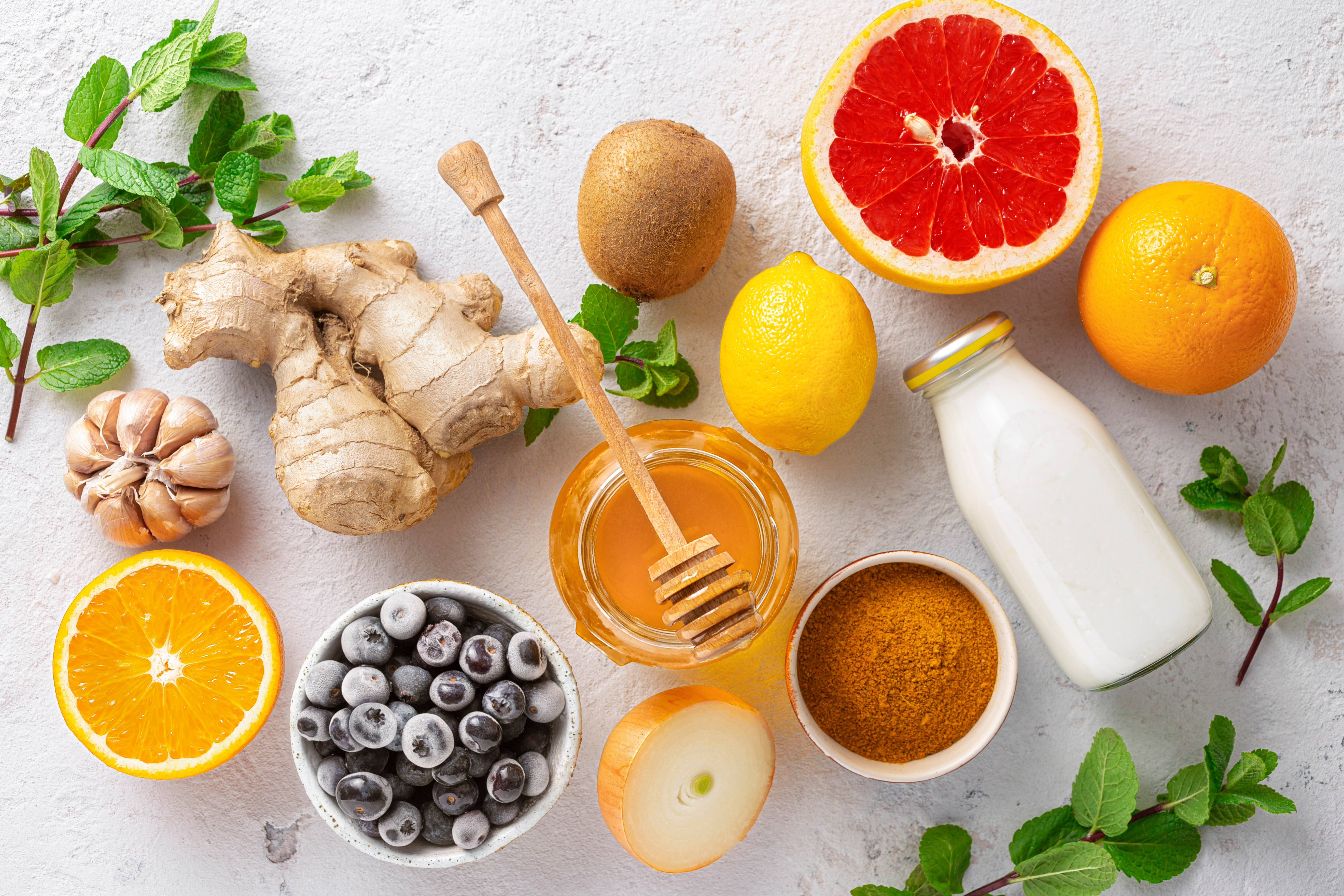 Immune boosting foods, including oranges, ginger, garlic, honey, kiwi, grapefruit, lemon, blueberries, onion, milk, and herbs